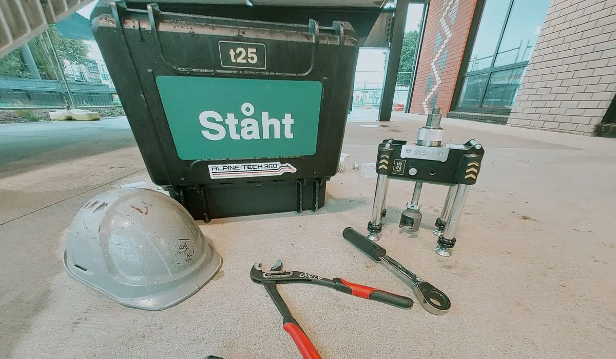 STAHT t25 pull tester and its Alpine-Tech 360 carry case on a job site, with a helmet and hand tools laid out on the concrete beside it
