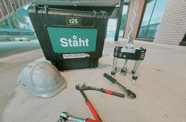 STAHT t25 pull tester and its Alpine-Tech 360 carry case on a job site, with a helmet and hand tools laid out on the concrete beside it